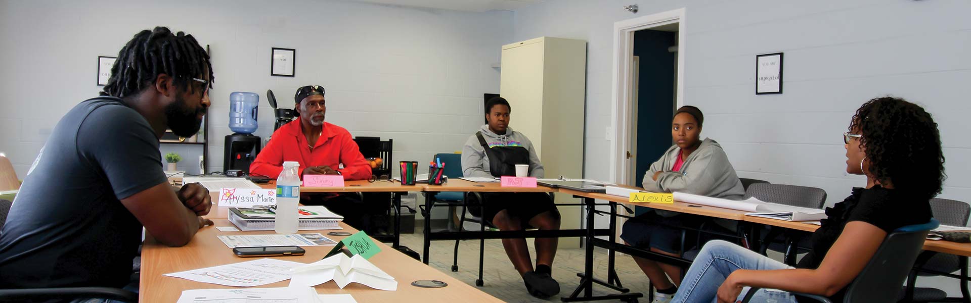 A Momentum group sits together at a U-shaped table discussing skills training.