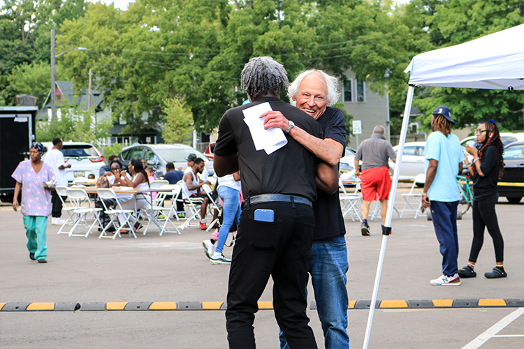 Two volunteers hug at an outdoor Urban Alliance event.