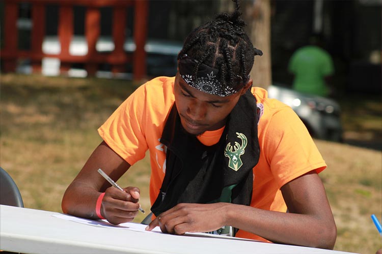 A young man reflecting and writing an exercise while participating in Life Camp.